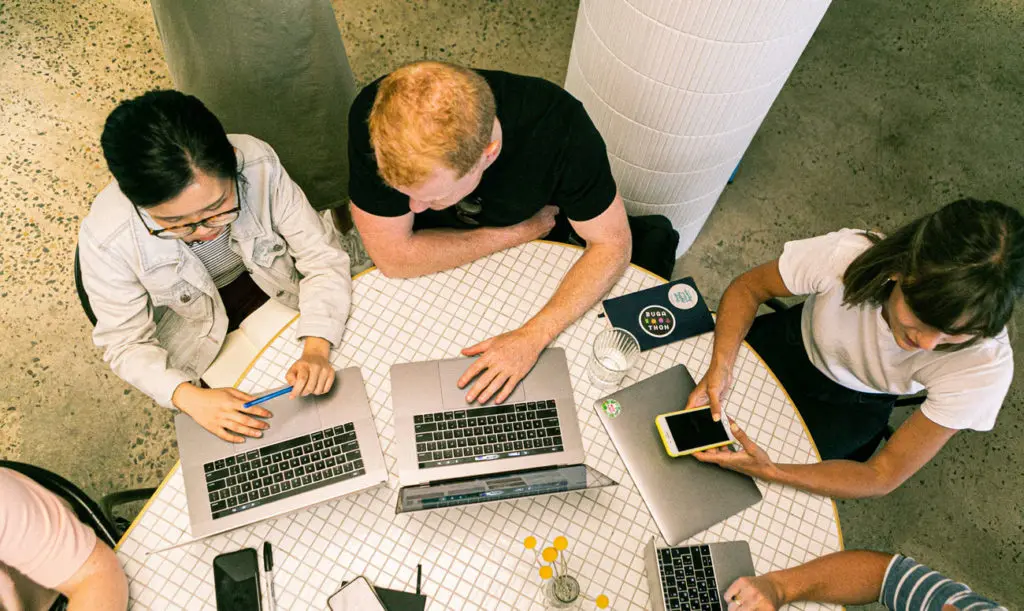 Trois personnes assises devant des ordinateurs discutent de projets d'éco-conception web chez digitik, entreprise engagée dans la sobriété numérique et le développement durable.